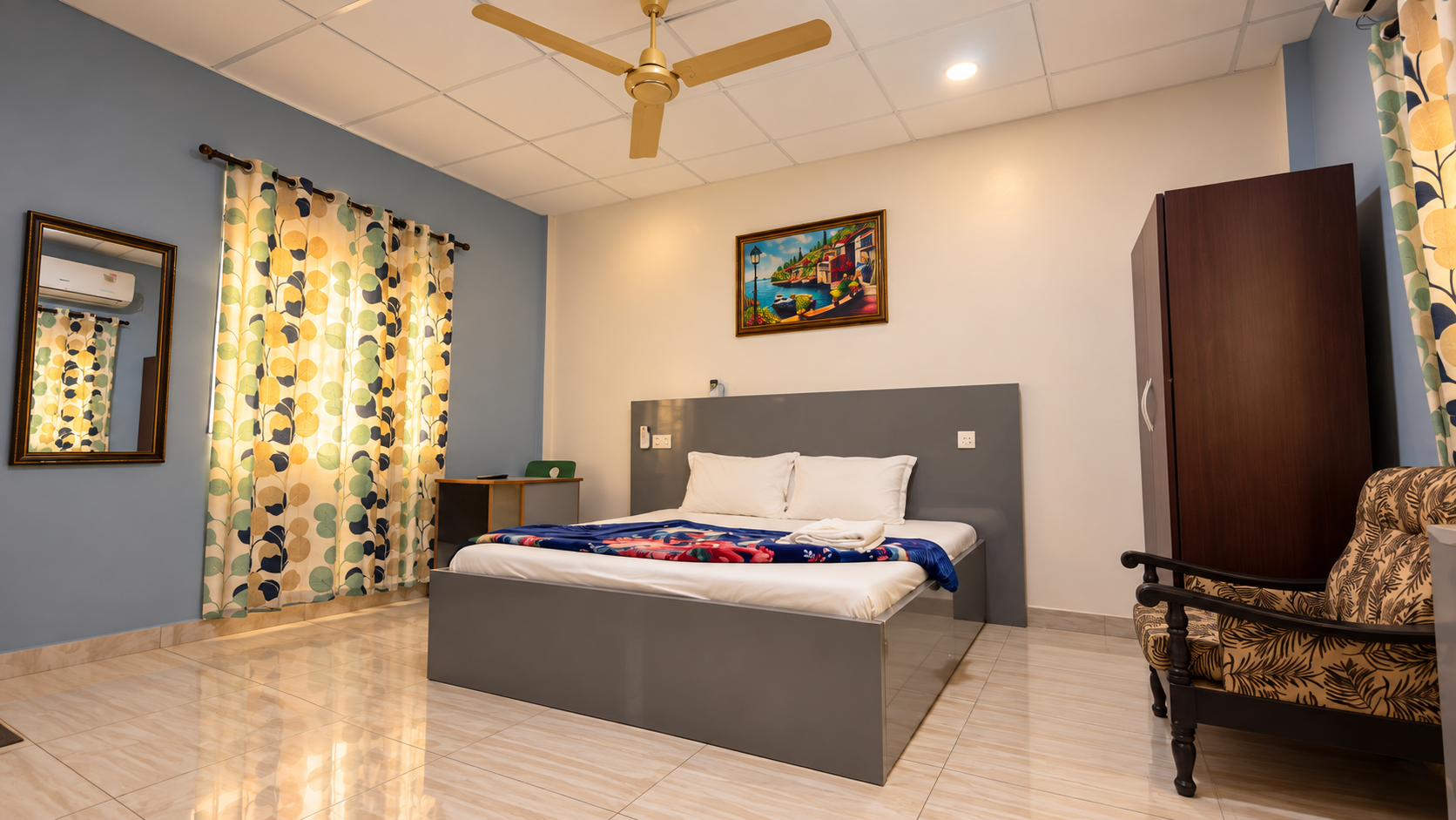 KUM Hotel guest room interior with double bed, ceiling fan and warm lighting